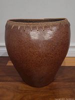 Front view of hand-made Indonesian pot showing rounded body and woven rim detail.