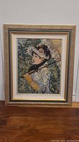 Full view of the framed Victorian needlepoint art depicting a lady in period clothing holding a parasol.