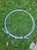Large coiled gray PVC pipe resting on grass, secured with black ties