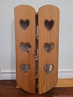 Shelf with closed doors showing six heart-shaped cutouts on two wooden panels.