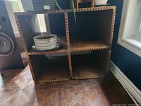 Full view of the vintage wooden shelf showing four square compartments, with decorative pots inside some compartments.