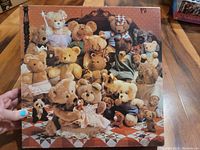 Photo showing one completed teddy bear themed jigsaw puzzle with various teddy bears on a checkered floor, held by hand.