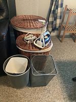 Two oval wicker baskets with fitted lids and white cloth lining, next to a small iron, a mesh metal basket, and a solid metal basket.