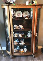 Front view showing oak frame, curved glass panels, and four interior shelves