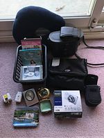 Full lot with Sony Cyber-shot camera box, Canon PowerShot camera case, Carl Schulz binoculars case, travel clocks, adapter kit, strapping and small bag