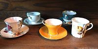 All four cups on matching saucers and one mug grouped showing overall lot