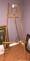 Front view of the bamboo easel showing the decorative curved design near the top and the bottom support shelf.