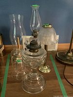 Overall view of the three lamps with varied glass and metal elements on wooden surface