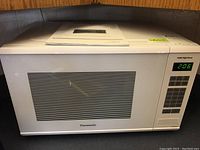 Front view of Panasonic microwave with door and control panel visible showing model and lighting on display.