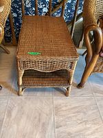 Front angled view of the wicker coffee table showing the woven top, apron, and lower shelf construction.