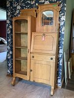 Front view of the vintage secretary cabinet showing the full piece with mirror and glass door.