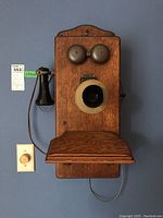 Front view of oak wall telephone showing bells, mouthpiece and handset