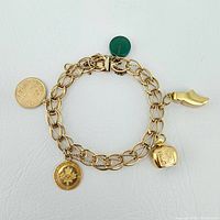 Overview of gold charm bracelet laid flat showing charms and clasp