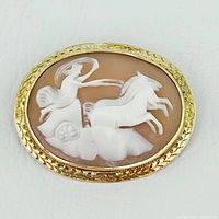 Front view of the oval cameo brooch showing carved relief and gold frame