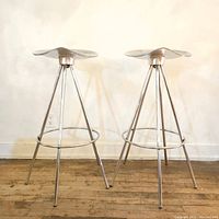 Front view of both stools showing saddle seats and tripod frames