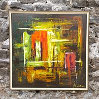 Front view of framed abstract acrylic painting leaning against stone wall