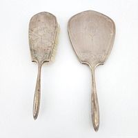 Front view of silver brush and mirror showing engraved decoration