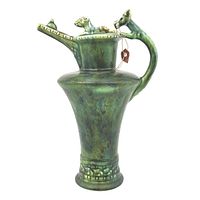 Full view of the green pottery jug showing shape, handle, spout and lid with animal sculpture.