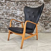 Front three-quarter angle view of chair showing beech wood frame, black leather seat and tufted button back.