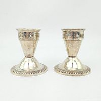 Front view of the pair of sterling silver candlesticks showing detailed pierced top rim and decorative base.