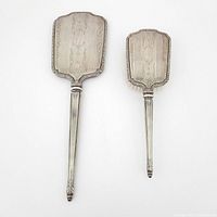 Top view of the sterling silver brush and mirror set showing engraved decorative backs and detailed handles