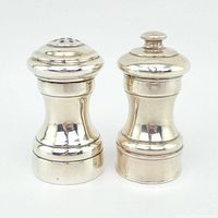 Front angle view of the sterling silver pepper grinder and salt shaker showing polished finish and design