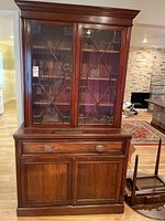 Front view of wooden buffet showing upper glass doors with geometric wood framing, middle drawer, and lower cabinet doors.