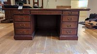 Front view of the large wooden desk showing nine drawers and central knee hole.