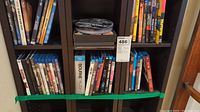Two rows of DVDs and Blu-rays in a dark wood shelving unit, close up view of titles.