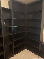 Three IKEA Billy black-brown bookcases arranged in a corner showing varying heights and widths, photographed in room corner with carpeted floor.