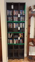 Front view of one black Ikea shelving unit holding DVDs and Blu-rays, showing signs of use and scratches.