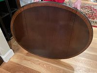 View of the oval wooden top of the drop leaf side table showing finish and overall shape