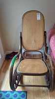 Front view of bentwood rocker chair showing cane seat and backrest, curved wooden arms and rockers.