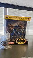 Photo showing the boxed Batman Limited 100th Edition action figure with Batman logos and artwork visible.