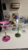 Five decorative colored glasses placed together showing their various painted festive designs and bases.