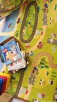 Photo showing a pile of children's books on a colorful play mat with roads and buildings design