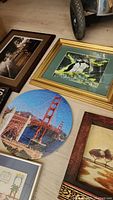 Framed print of puffins with gold frame, rustic bird painting, and San Francisco puzzle plate on floor.