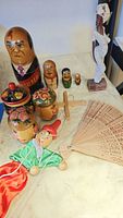 Overview of the wooden items on a table including nesting dolls, jars, cross, fan, puppet, and a woman figurine