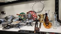 Shelf view of assorted kitchen and household items including cookware, glassware, and utensils.