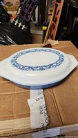 Photo of blue Pyrex casserole dish with white lid showing blue floral pattern