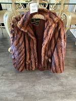 Front view of the brown mink fur cape jacket hanging on a hanger, showing collar and fur texture.