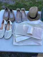 All footwear, hat, and shoe holder items displayed on a table outdoors with grass in background.