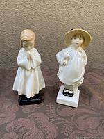 Front view of two Royal Doulton figurines, Bedtime and James, showing girl praying on left and boy with hat and dog on right.
