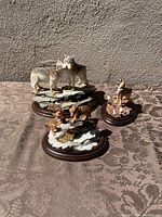Three wolf figurines displayed together in natural sunlight on patterned surface showing the condition and details of each piece.