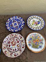 Overview of all four majolica decorative plates on surface, showing various colors and designs