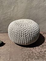 Side view of the round knitted cotton cord floor pouffe footstool showing the chunky knit texture and shape.