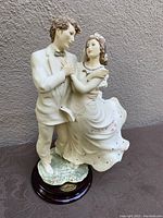 Front angle view of the dancing couple figurine showing details of faces, clothing, and base.