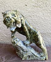 Front and left side view of the jade lion sculpture showing detailed carving and the open mouth with chipped teeth.