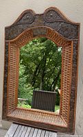 Full front image of large rectangular mirror showing wicker, wood and tin elements of the frame.