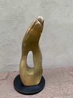 Front view of the soapstone sculpture showing organic abstract shape, hollow center, and polished brown surface on black spinning base.